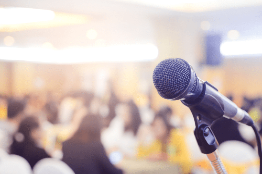 a microphone stands before a full conference room