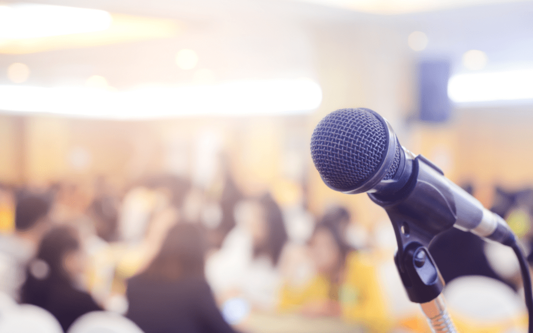 a microphone stands before a full conference room