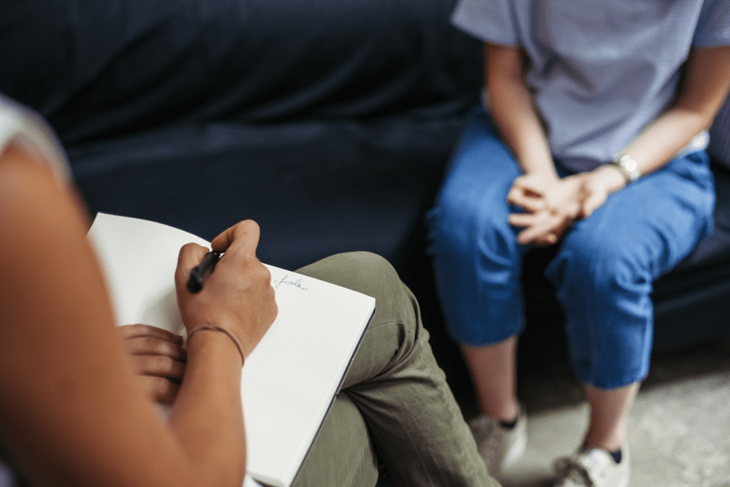 a therapist takes notes as their patient sits across from them